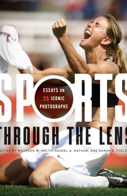 A woman athlete celebrates passionately on a field, holding her jersey in the air. The cover of a book titled "Sports Through the Lens" overlays the image.